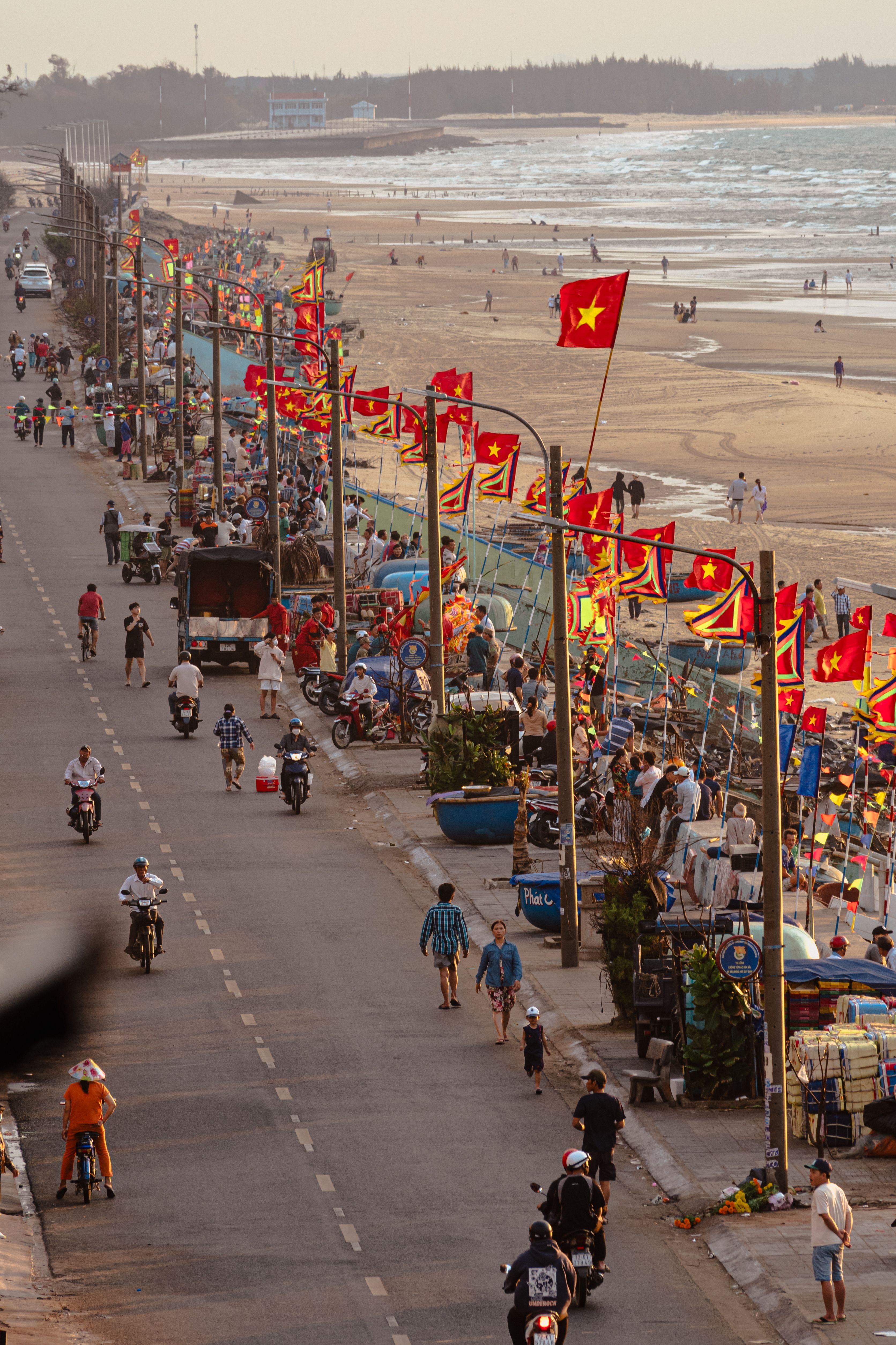 Colorful street scene by Lang Phuoc Hai beach with flags and people enjoying the coastal view.