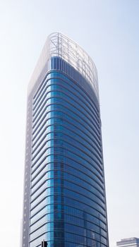 Futuristic glass skyscraper in downtown cityscape with a unique architectural facade.