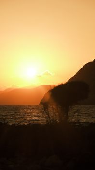 Scenic view of a coastal sunset with mountain and ocean silhouettes, ideal for travel visuals.