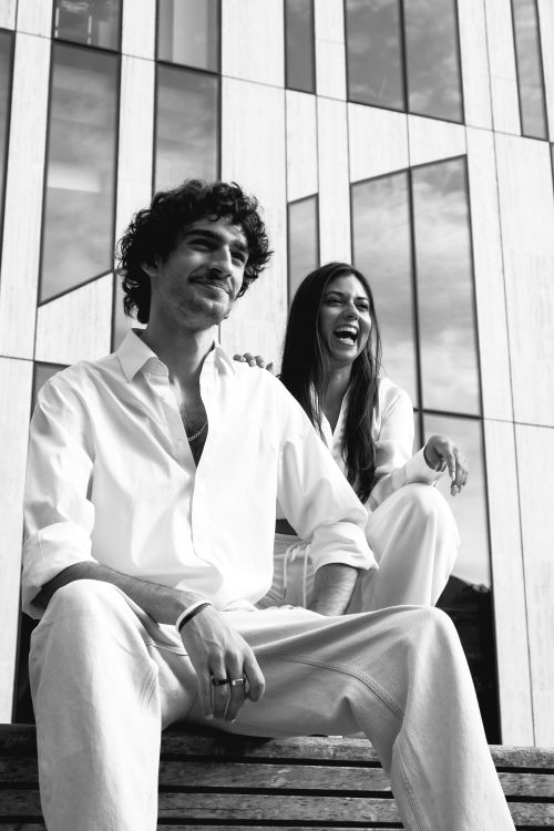Free Happy duo sitting outdoors, enjoying a casual moment in Düsseldorf's modern architecture. Stock Photo