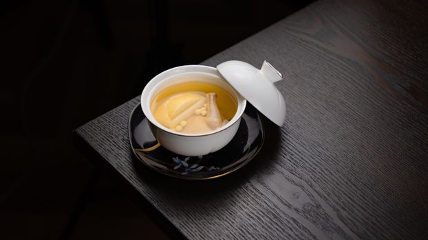 Delicious gourmet soup served in a white ceramic bowl on a dark wooden table, perfect for cozy meals.