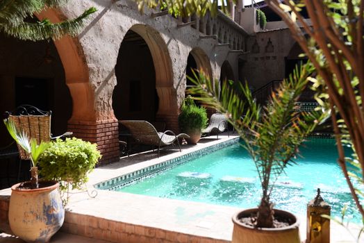 A tranquil luxury courtyard featuring a beautiful swimming pool and elegant architecture under a sunny sky.
