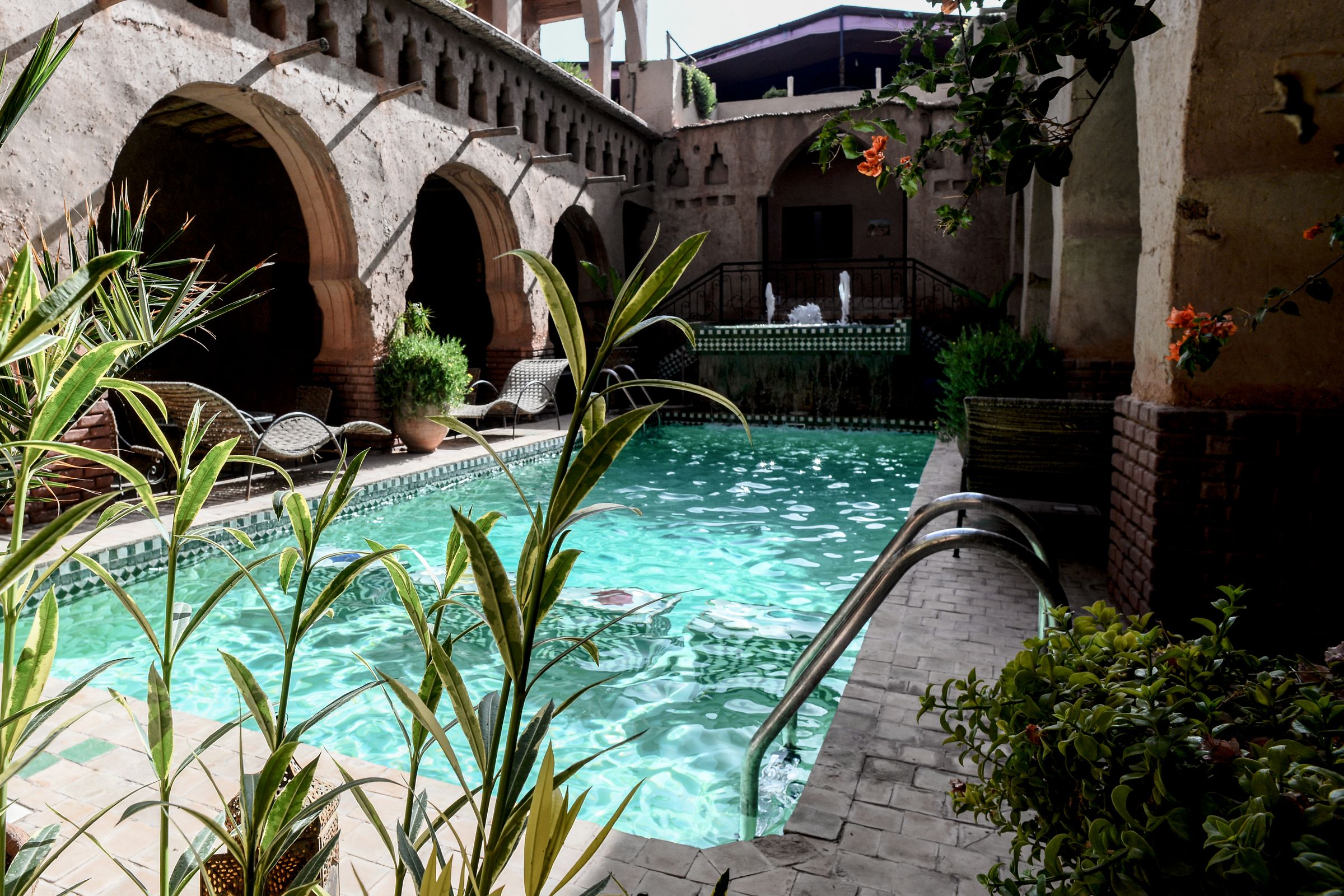 The pool courtyard of the riad, framed by earth-plaster arcades and palms