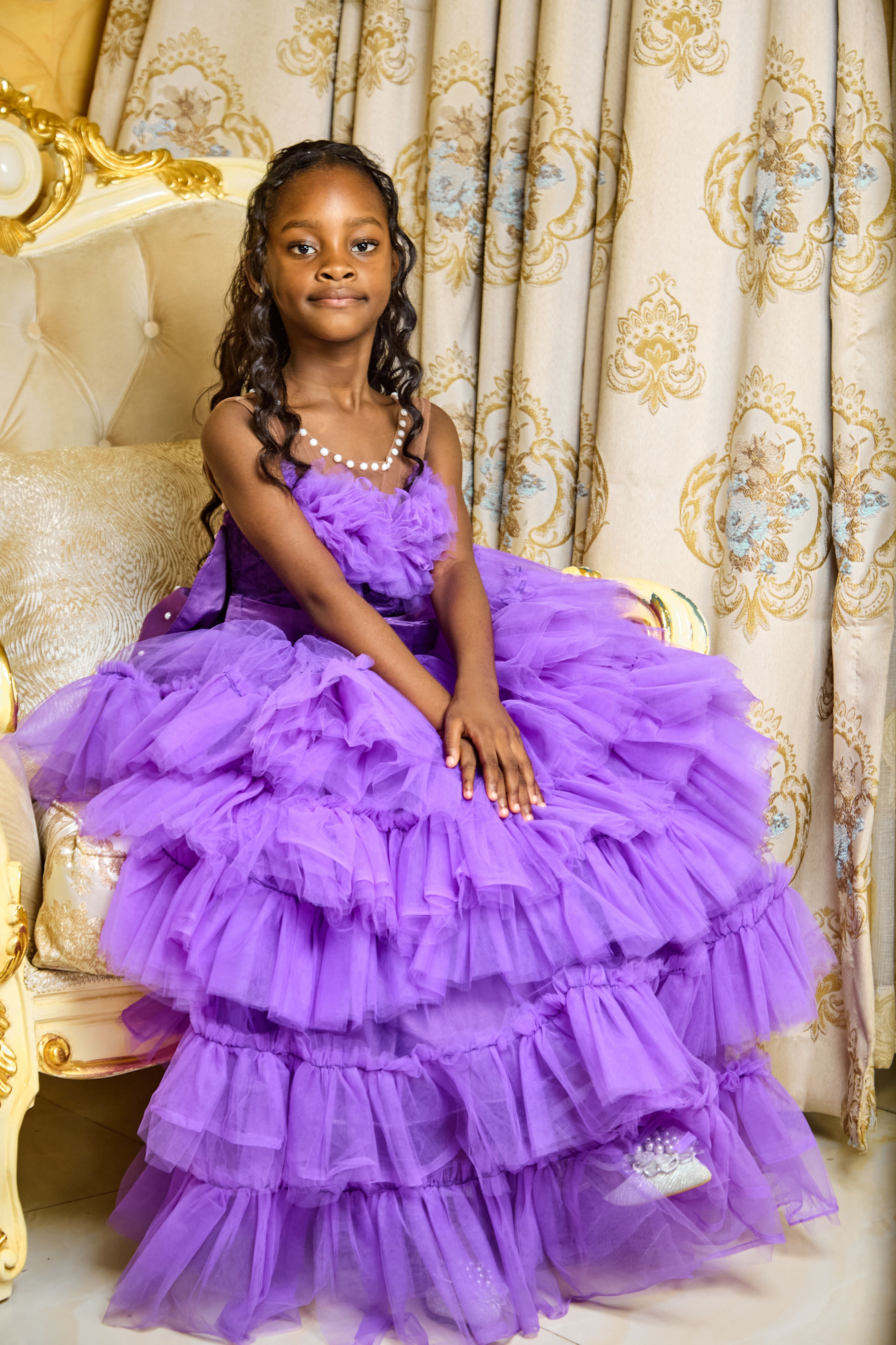 A little girl in a purple dress sitting on a chair · Free Stock Photo