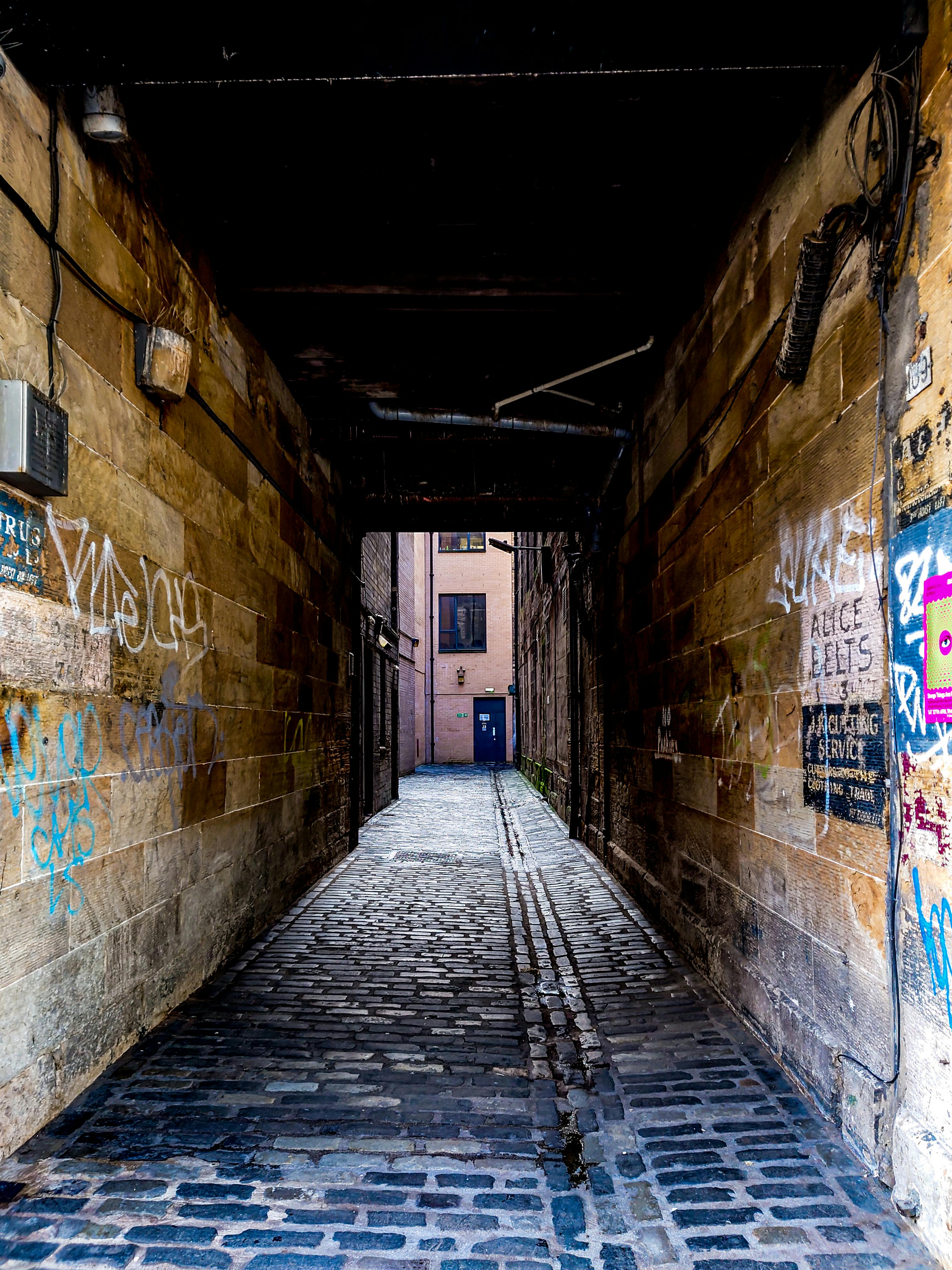 a narrow alley with graffiti on the walls