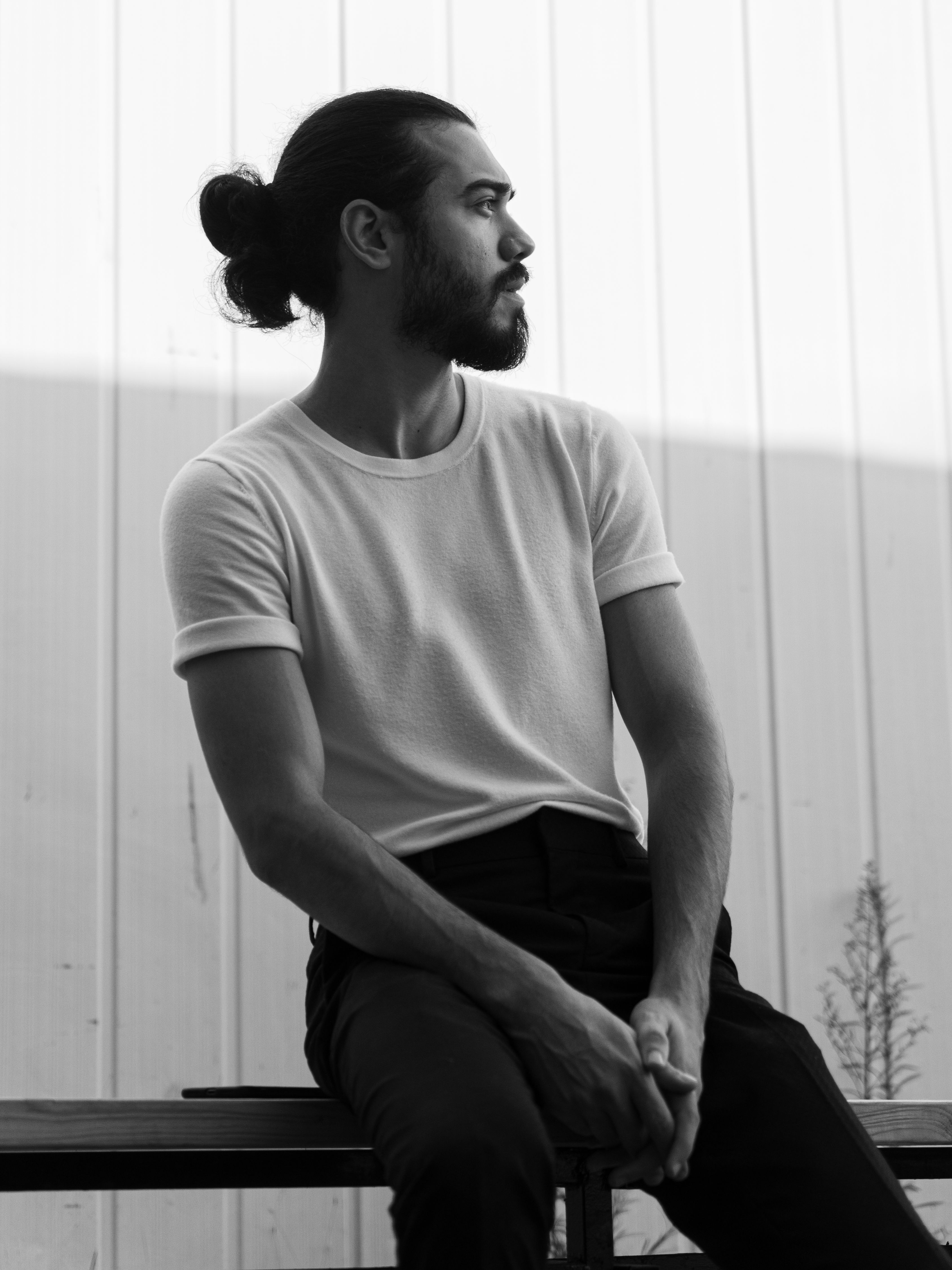 A black and white portrait of a man sitting and looking away, captured in a pensive mood.