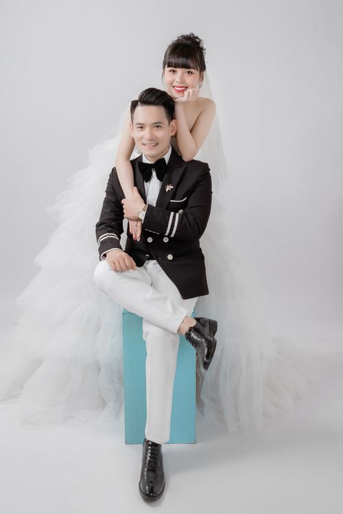 Free A joyful bride and groom in stylish formal wedding attire posing against a light background. Stock Photo