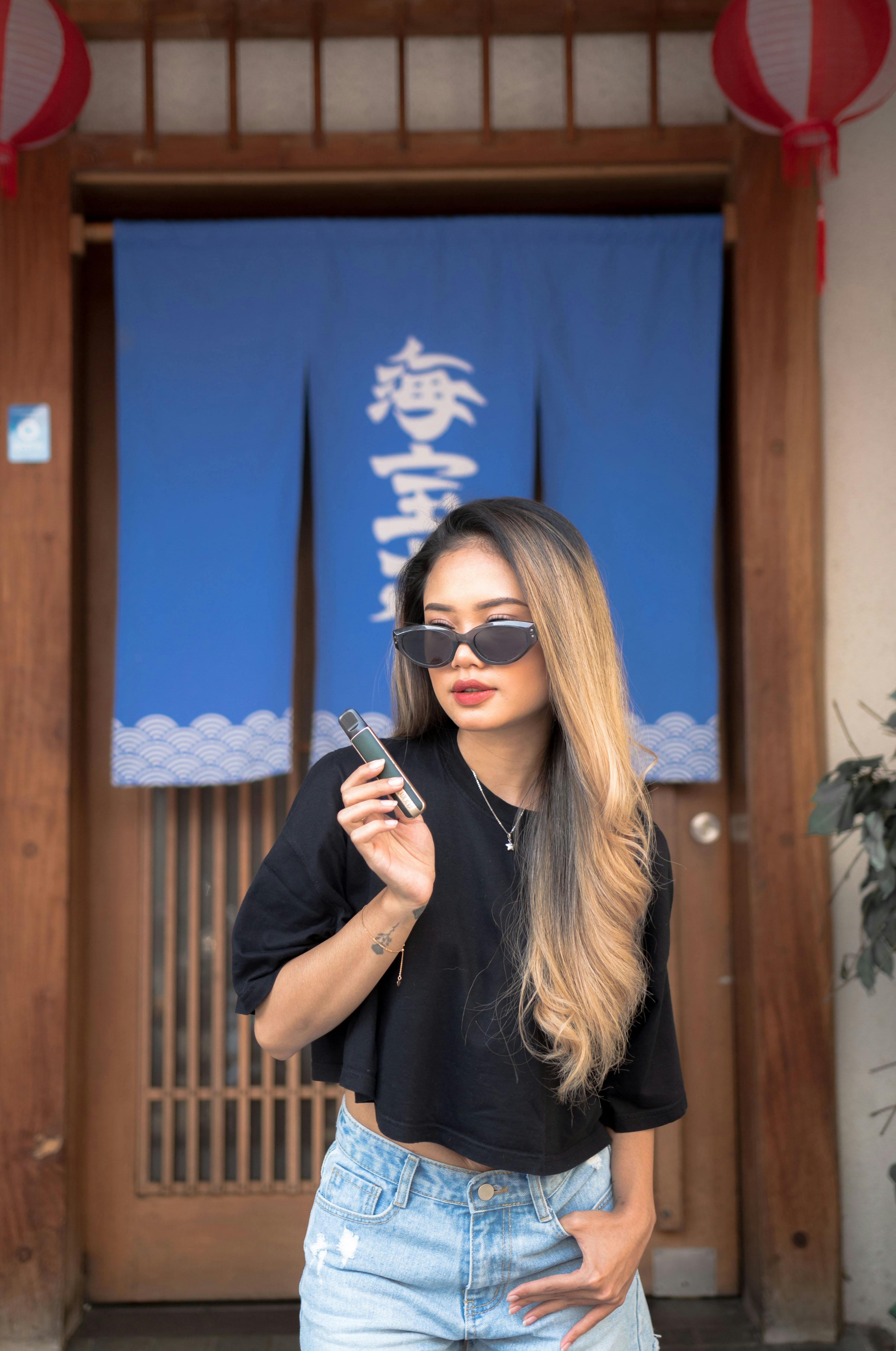 a woman in sunglasses and a black top is standing in front of a door