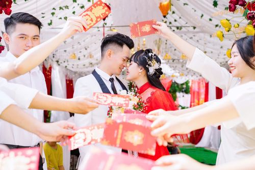 Free Bride and groom surrounded by friends holding red envelopes at an Asian wedding. Stock Photo