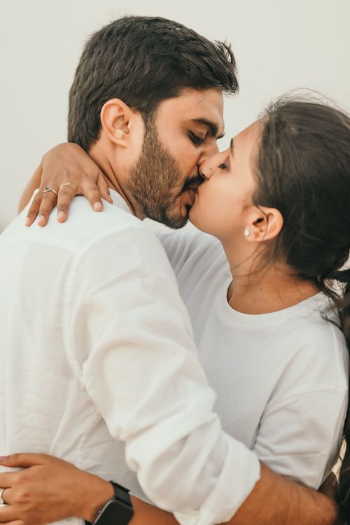 Free A loving couple shares a tender kiss while embracing indoors, showcasing intimacy and romance. Stock Photo