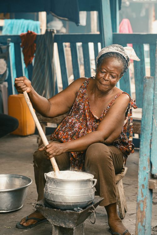Free Woman cooking traditionally at a Kumasi market, showcasing Ghanaian culture. Stock Photo