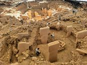 Ancient archaeological site Göbekli Tepe under excavation, showcasing stone pillars and historical ruins.