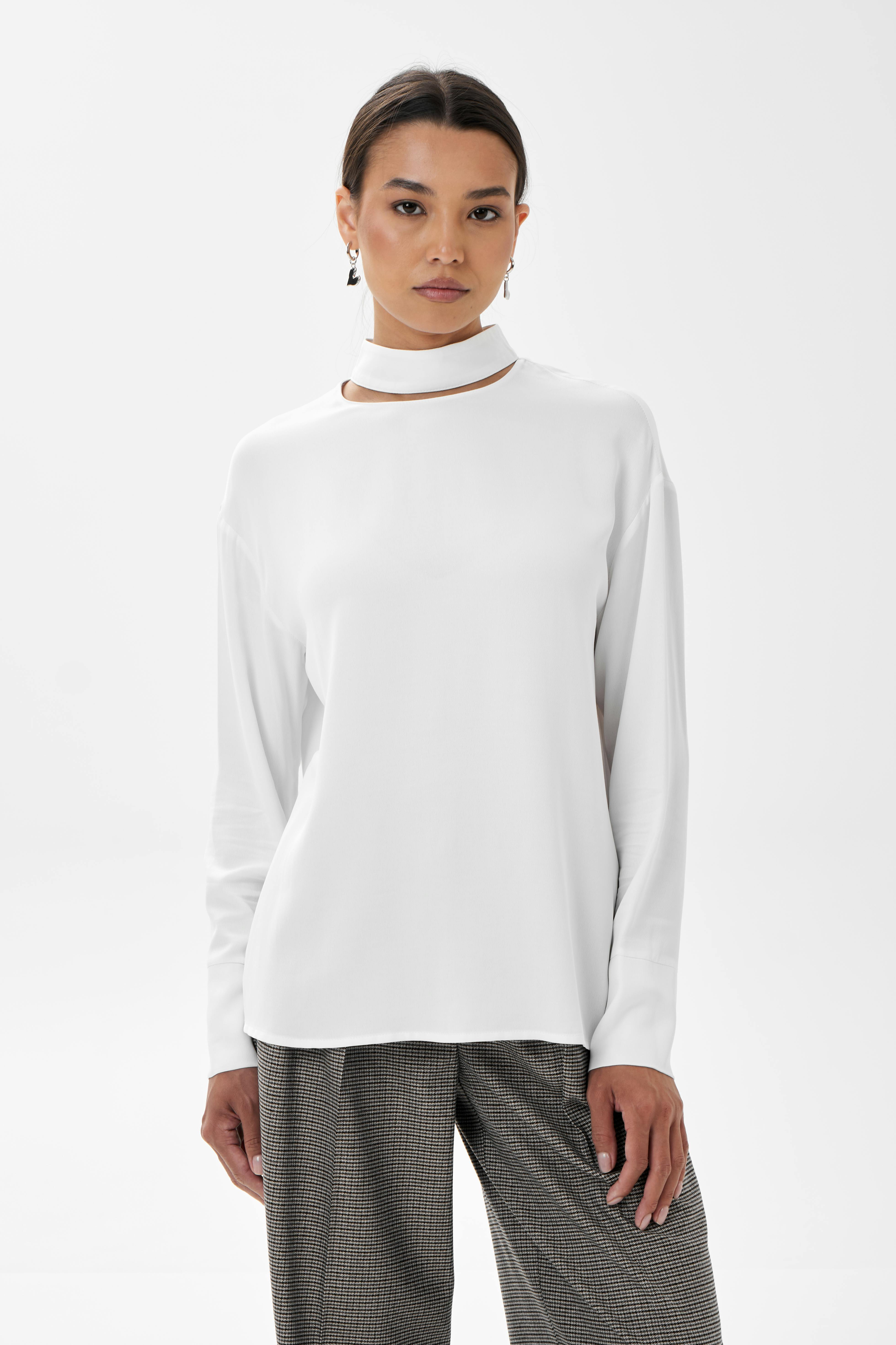 A stylish woman in a studio modeling a chic white sweater and pants.