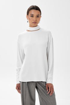 A stylish woman in a studio modeling a chic white sweater and pants.