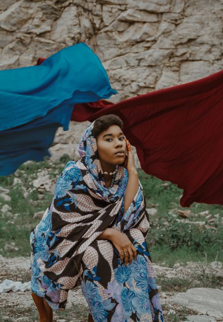 Portrait of an African woman wearing a vibrant scarf in a natural outdoor setting.