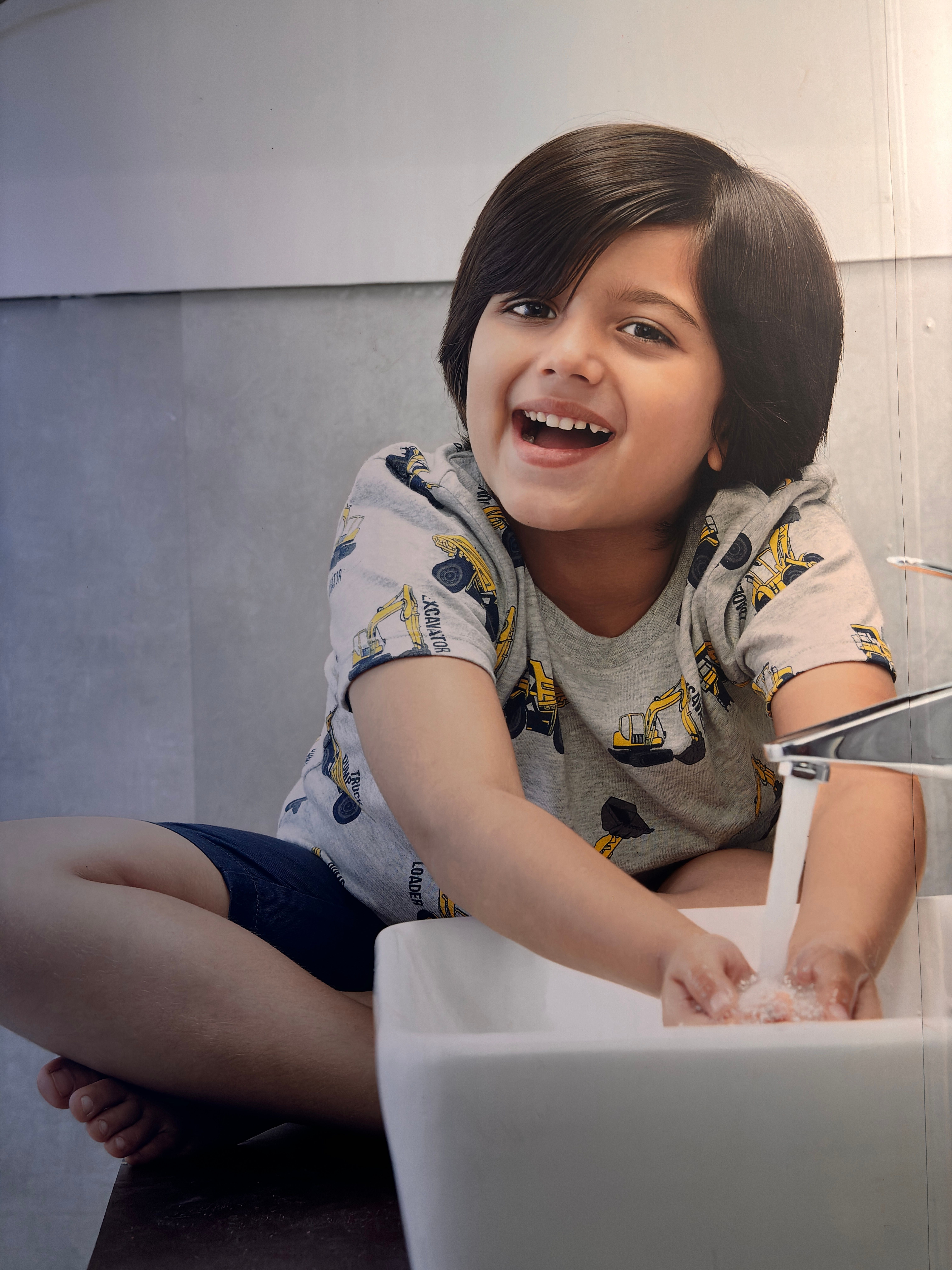 A cheerful child washing hands at the bathroom sink, promoting hygiene and fun indoors.