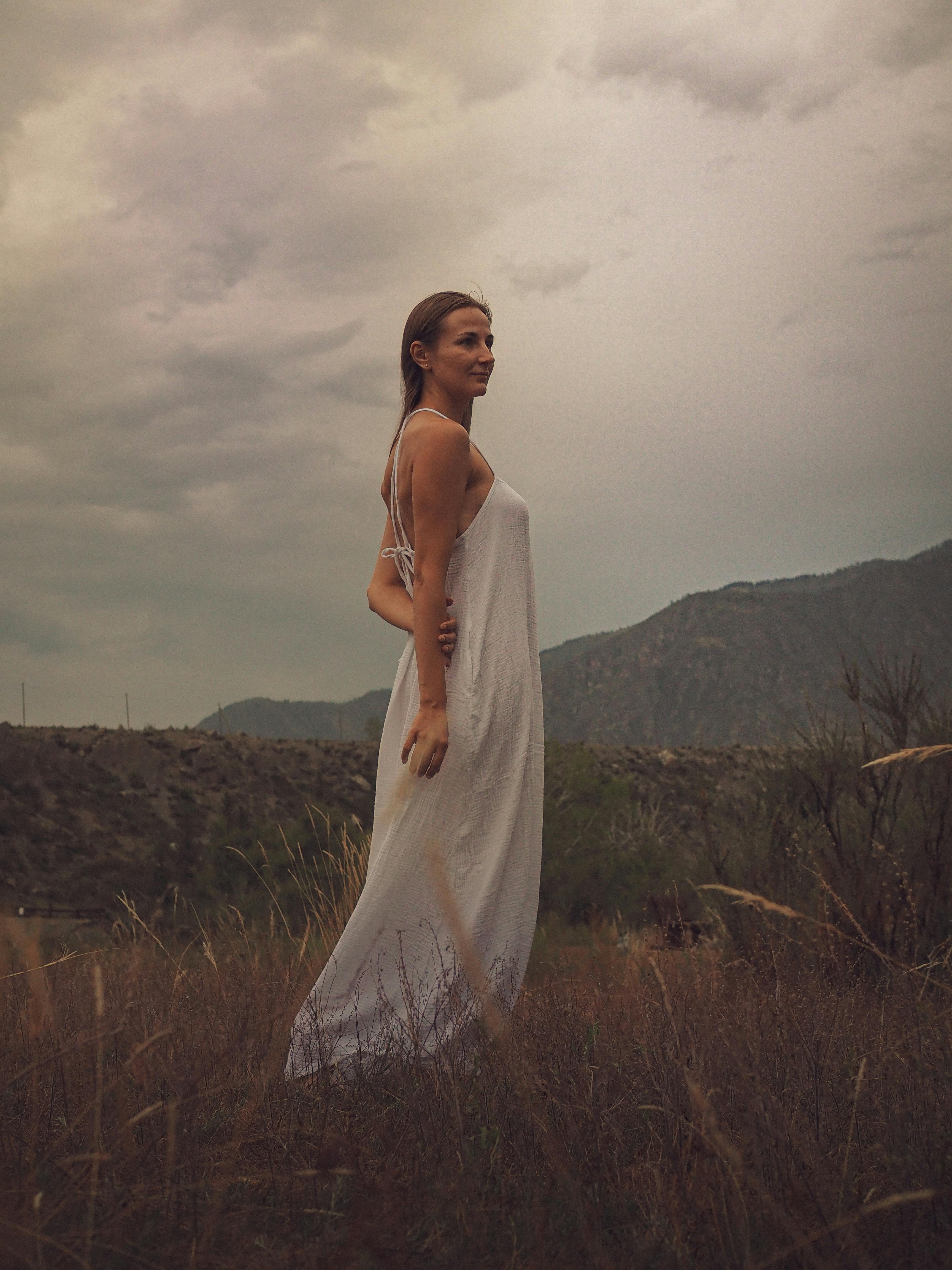 Woman in Backless Dress Standing Beside Rock Formation  Free Stock Photo