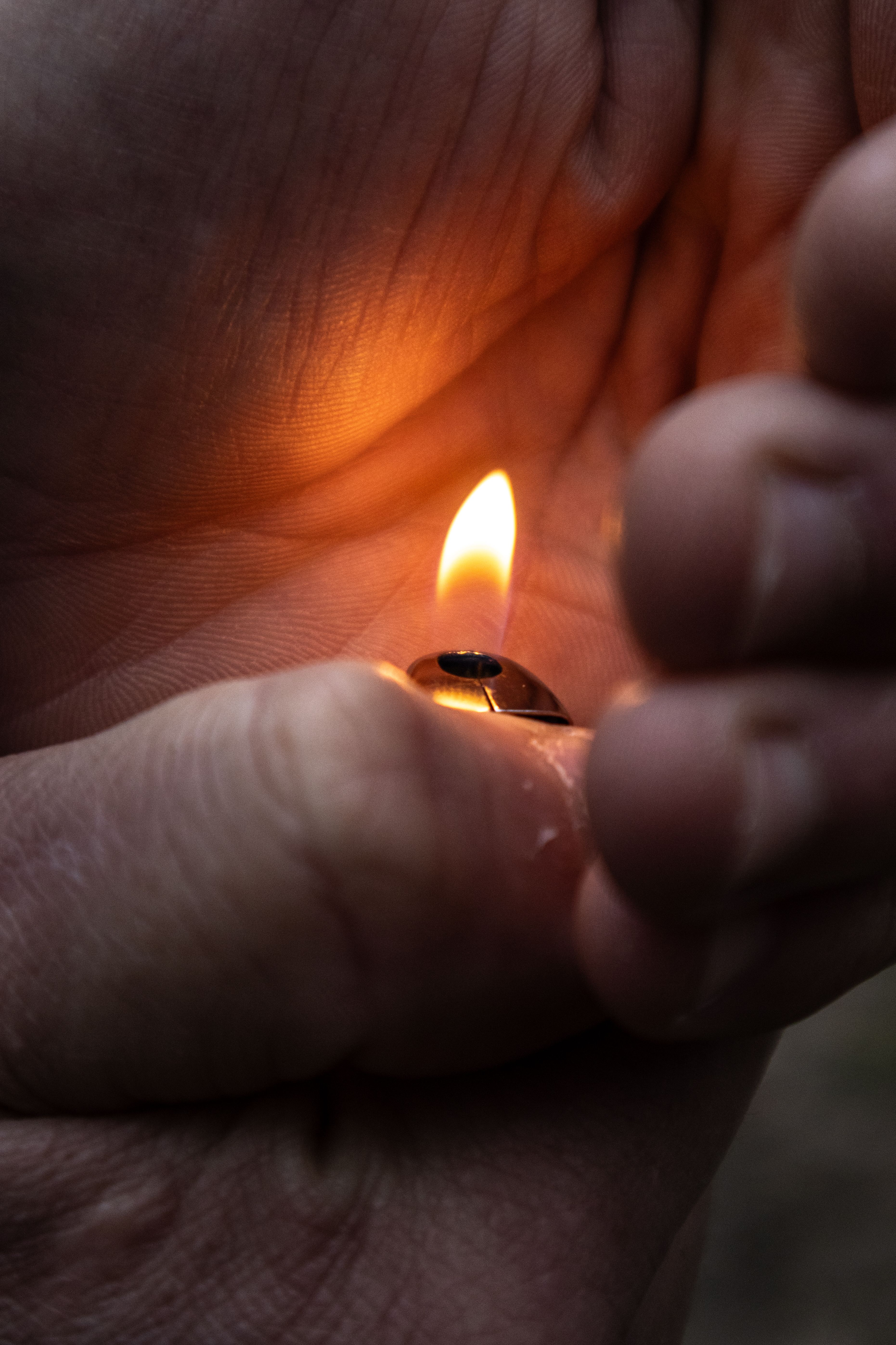Hands cupping a lighter flame, emphasizing warmth and protection.