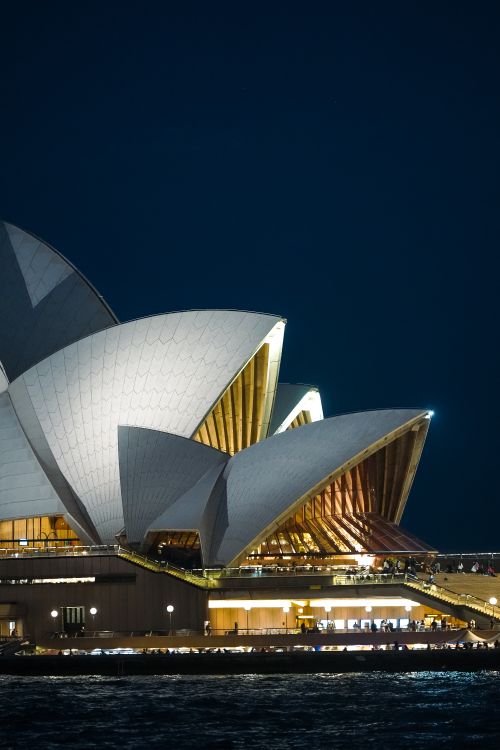 Free Iconic Sydney Opera House with illuminated sails at night, showcasing modern architecture. Stock Photo