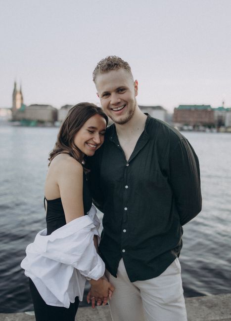 Romantic couple embracing by the water with a cityscape backdrop, perfect for depicting love and togetherness.