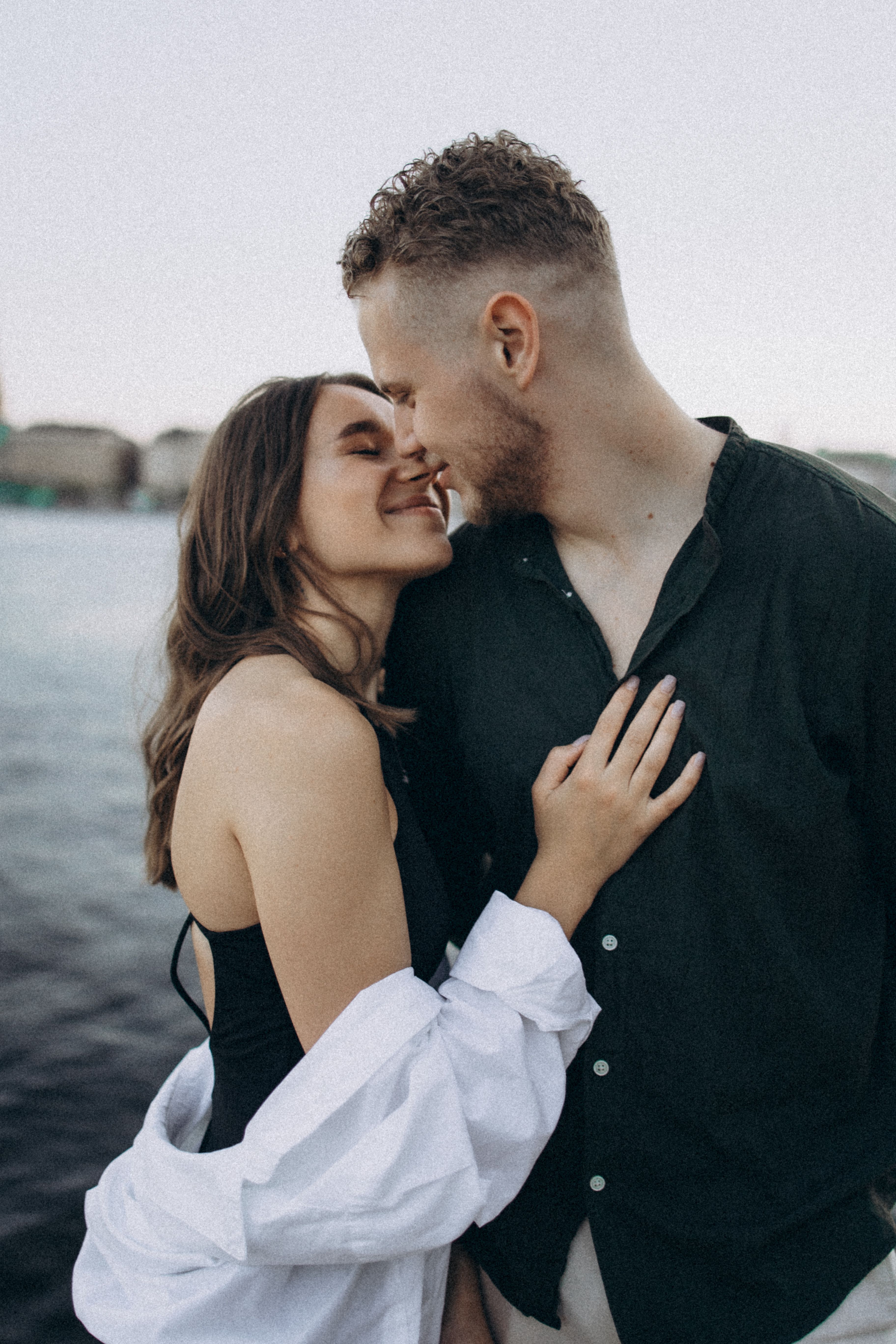 A loving couple enjoying a tender moment by the water's edge.