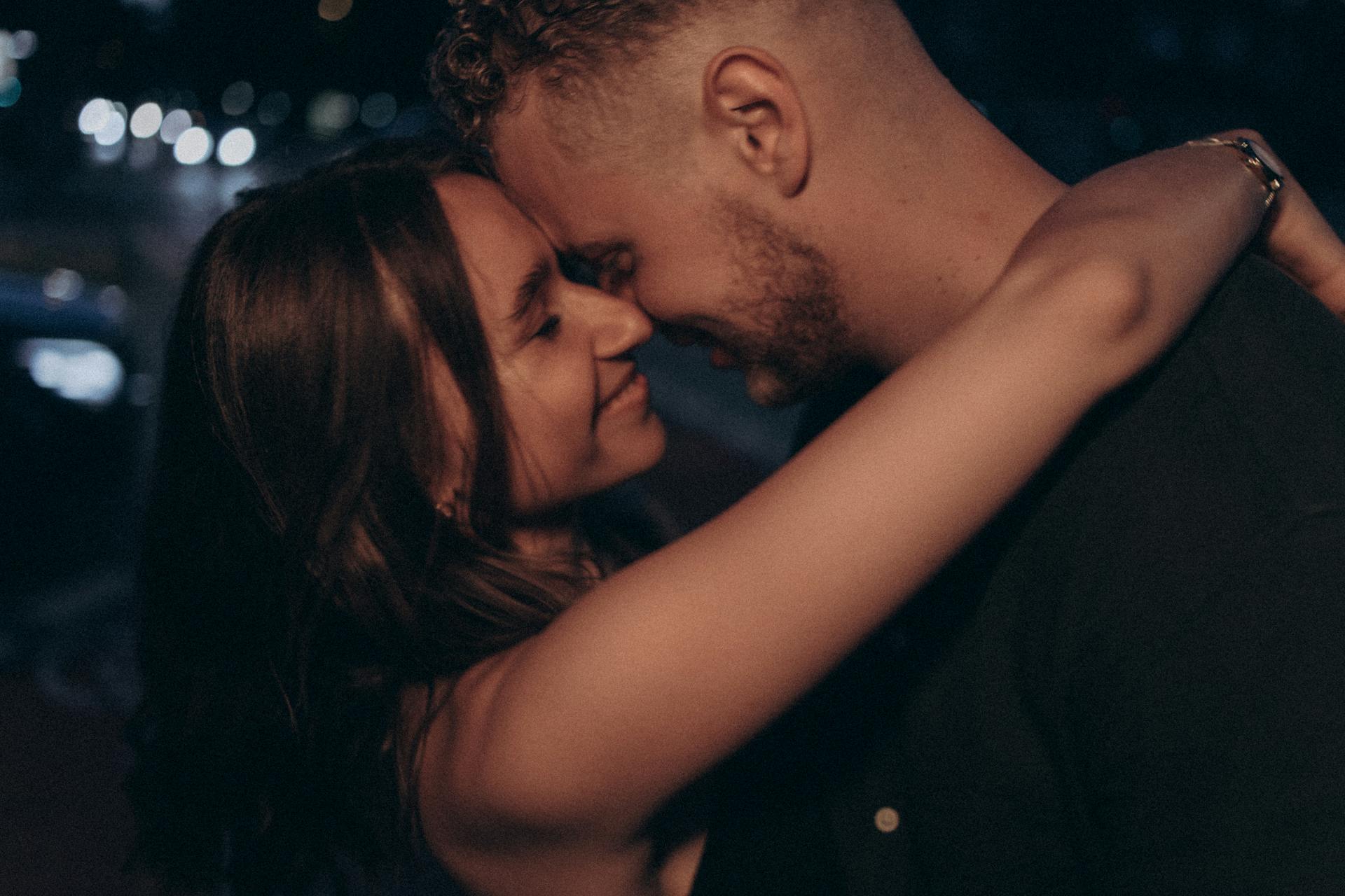 A couple shares a tender embrace on a city street at night, embodying love and intimacy.