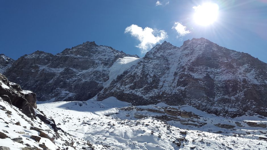 Majestic snowy mountain peaks under bright sunlight at Stelvio, Italy, showcasing winter beauty.