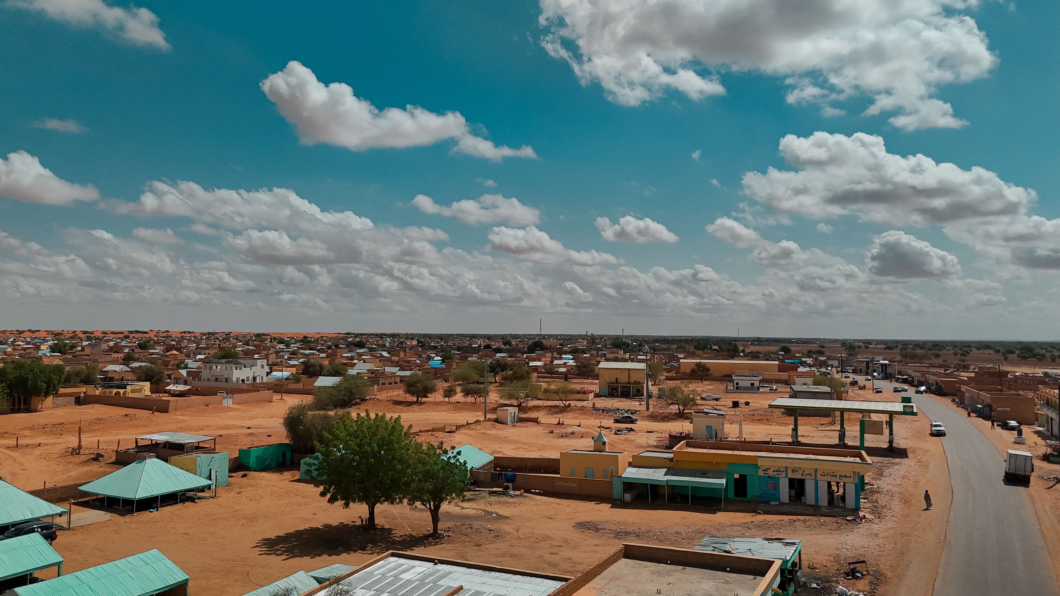 Scenic aerial view of a rural village with scattered houses under a vibrant blue sky with clouds.