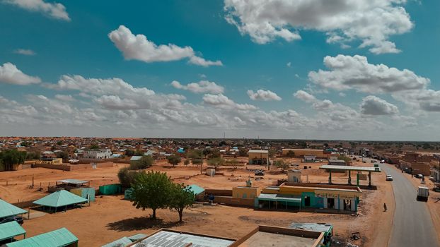 Scenic aerial view of a rural village with scattered houses under a vibrant blue sky with clouds.