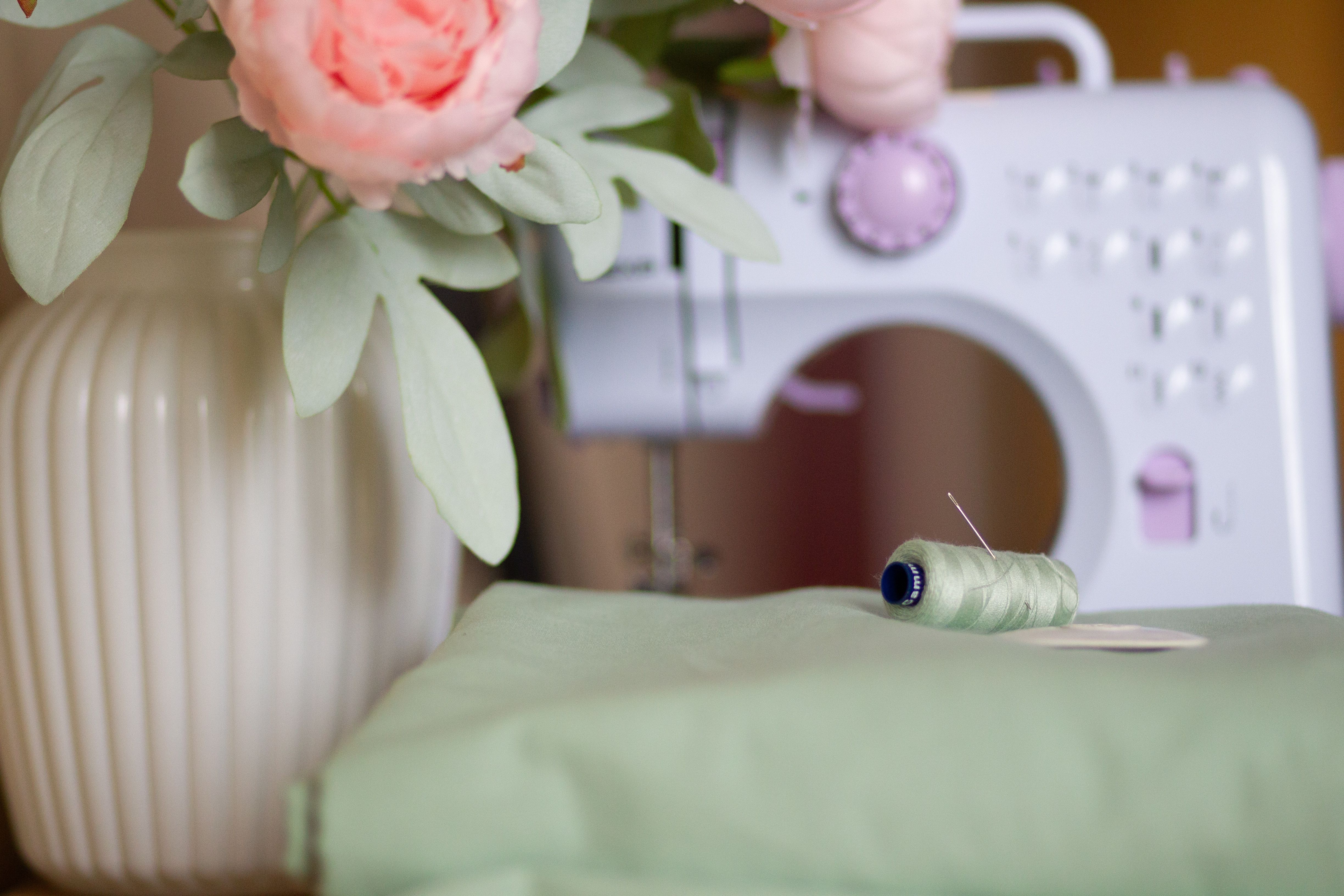 Chic sewing setup with a vintage machine, flowers, and thread.