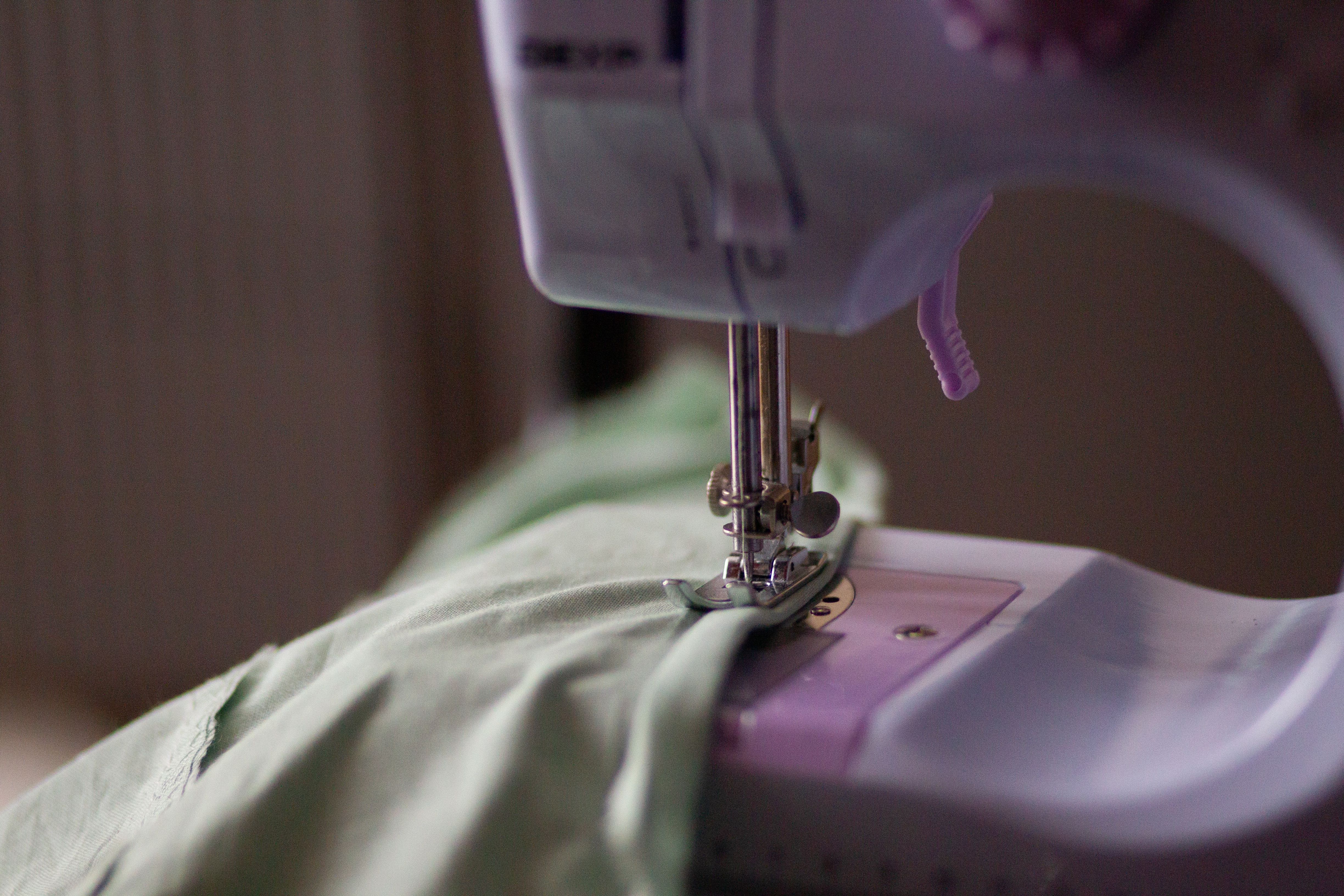 Detailed view of a sewing machine needle stitching green fabric. — Maynard Longarm Quilting