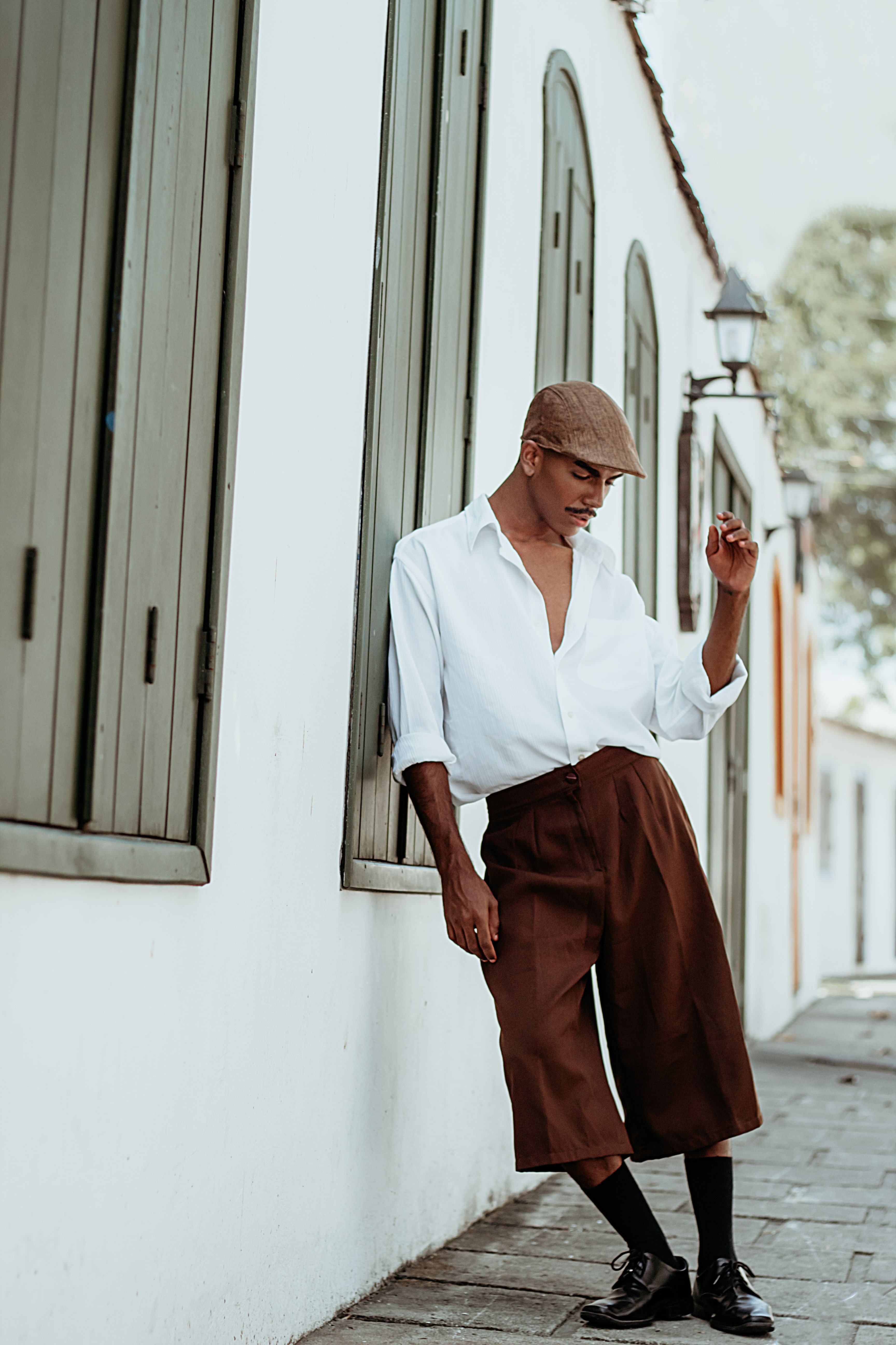 A fashionable young man poses confidently in the street wearing vintage-inspired attire.