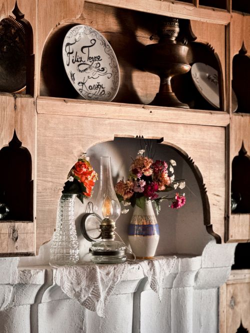Free Vintage decor with an oil lamp, floral vases, and antique wood shelves. Stock Photo