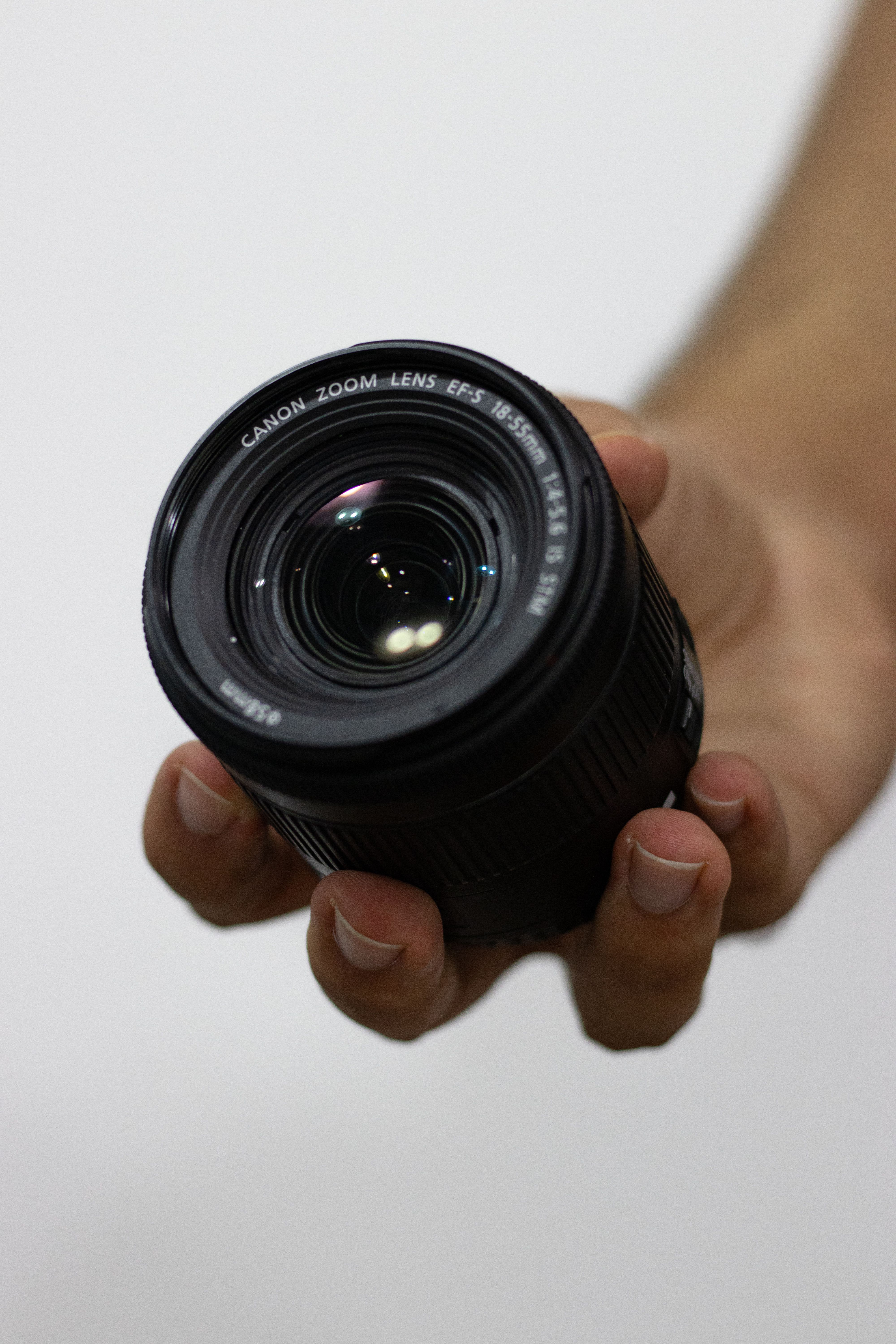 Hand holding a camera lens, showcasing photography equipment.