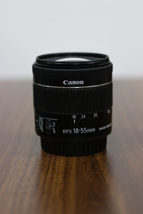 Free Black camera lens standing on a wooden surface, showcasing focus and simplicity in photography equipment. Stock Photo