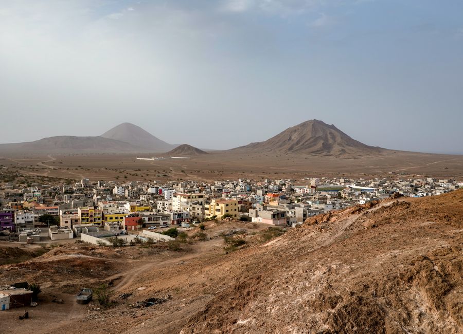 Aerial view of a city nestled in an arid landscape with distant mountains under a clear sky.