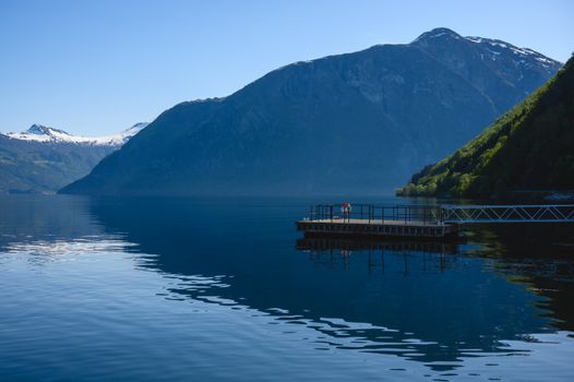 Tranquil scene of a dock by a fjord with mountains in Eidsdal, Norway.