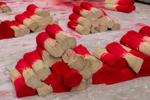Free Piles of red-tipped incense sticks on a concrete floor, ready for packaging. Stock Photo