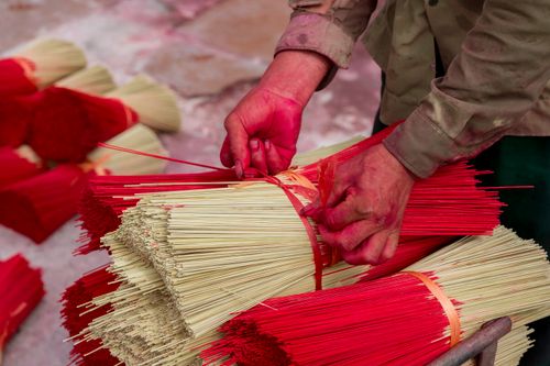Free Close-up of hands bundling red incense sticks, highlighting traditional craftsmanship. Stock Photo