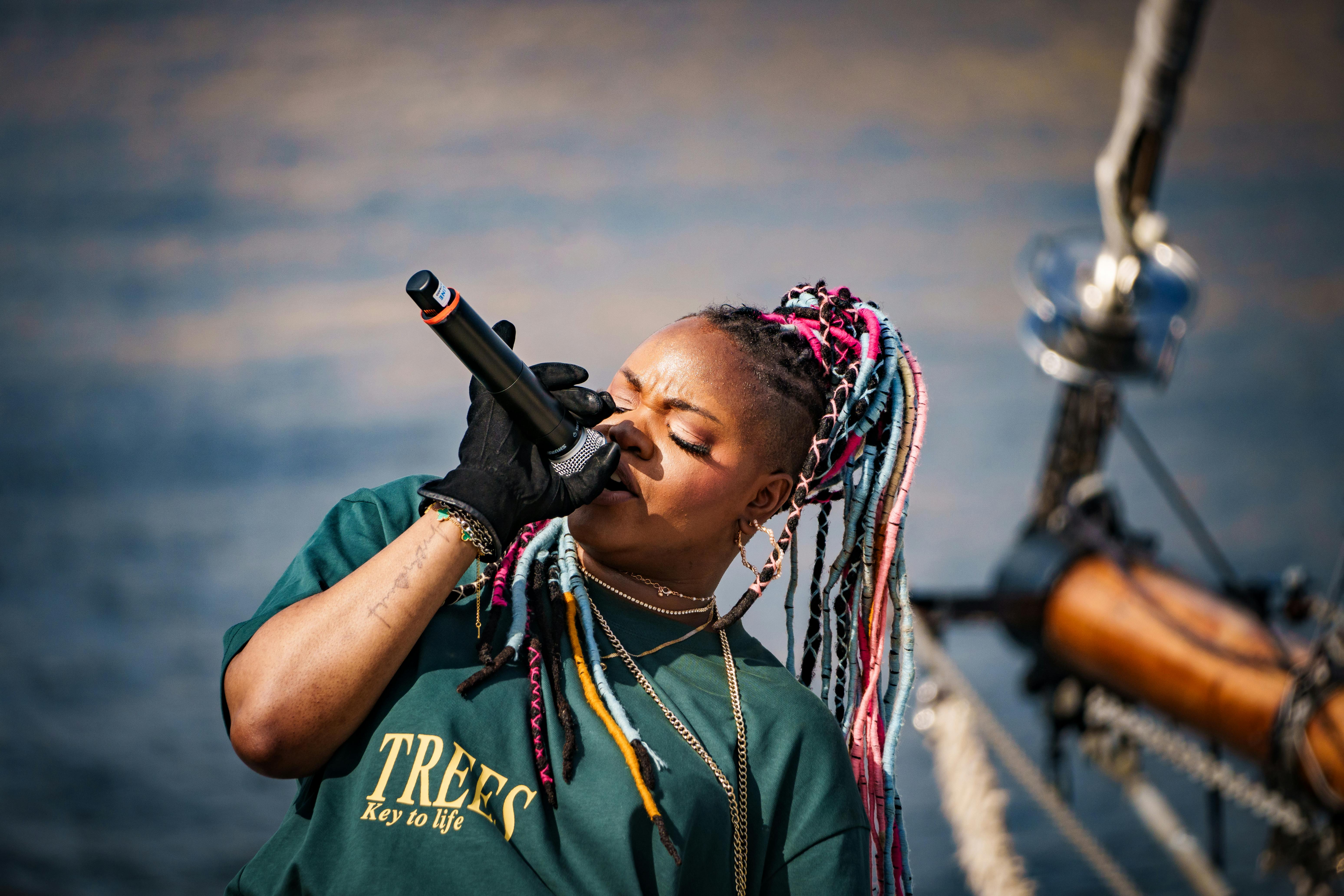 a woman with dreadlocks is singing on a boat