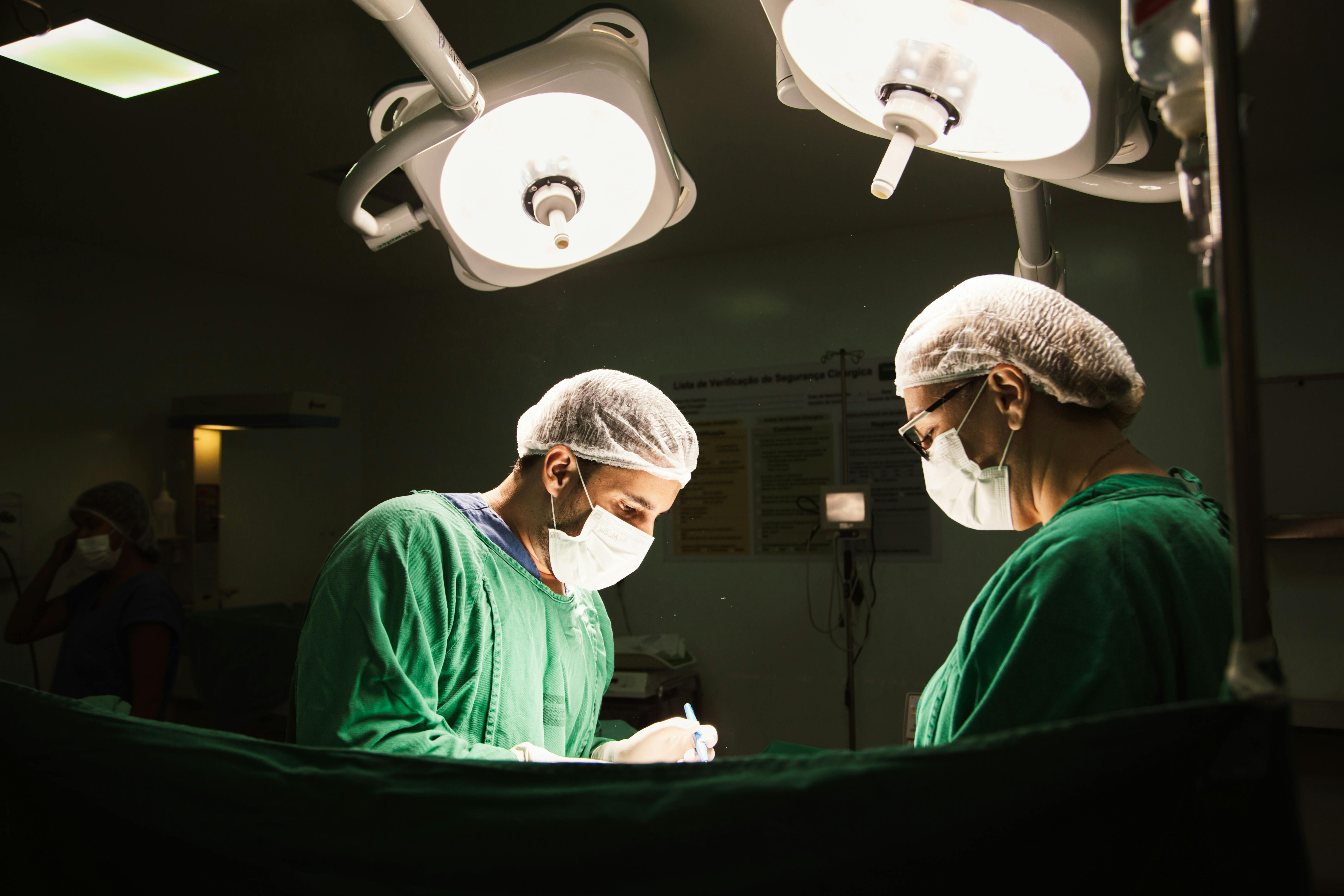 two surgeons in green scrubs are working in an operating room