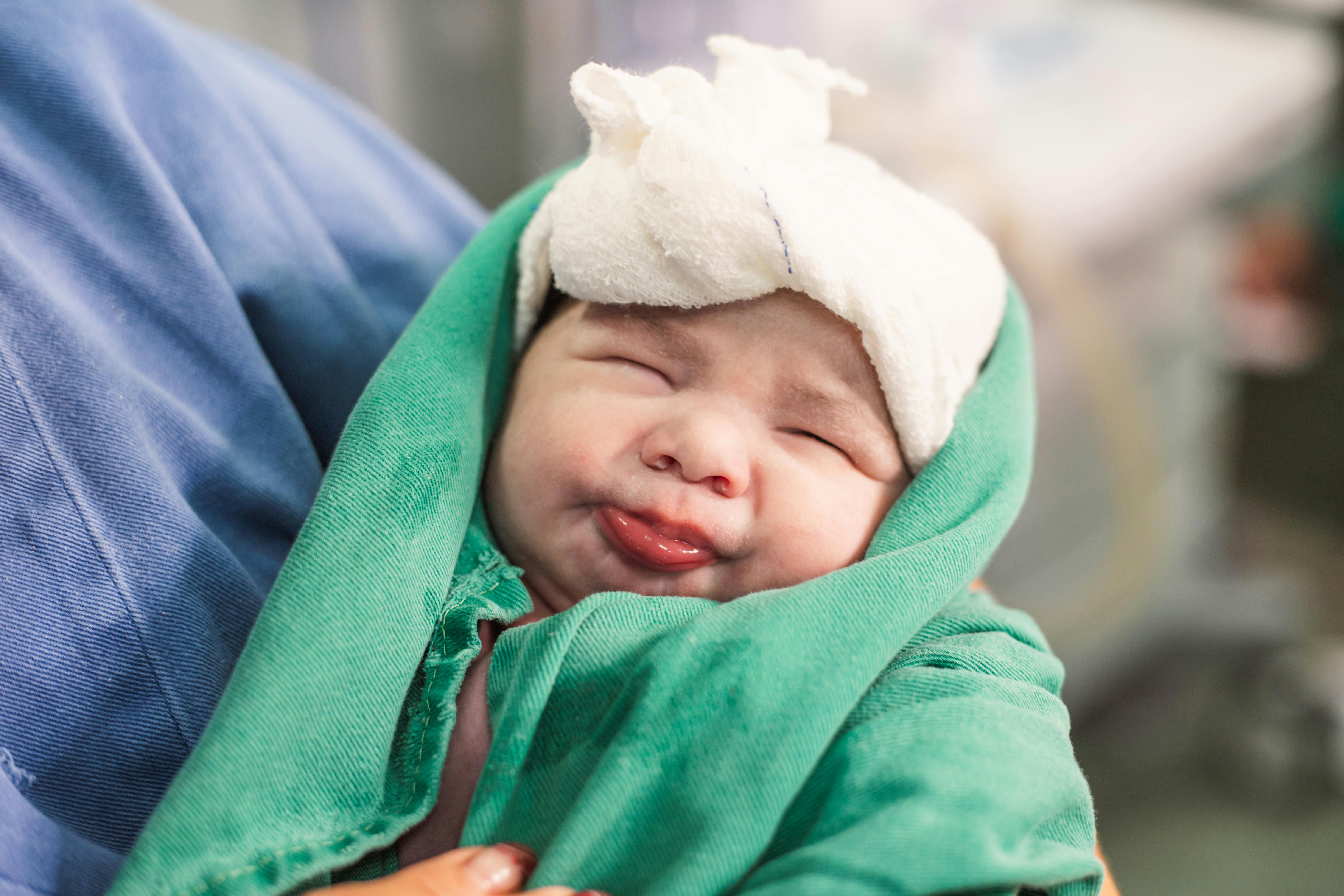 a baby in a hospital bed with a green bandana