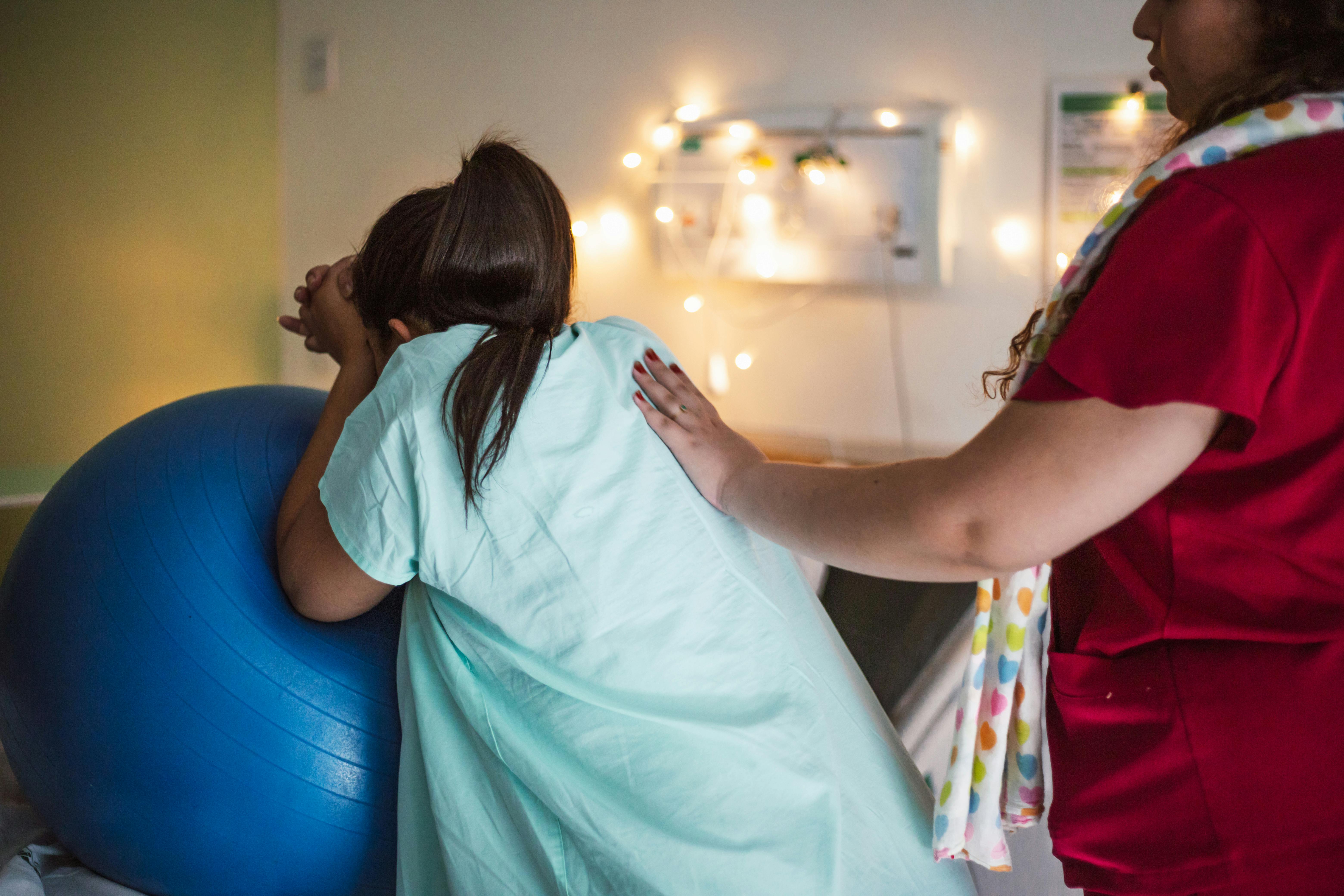 a woman is holding a ball in a hospital room