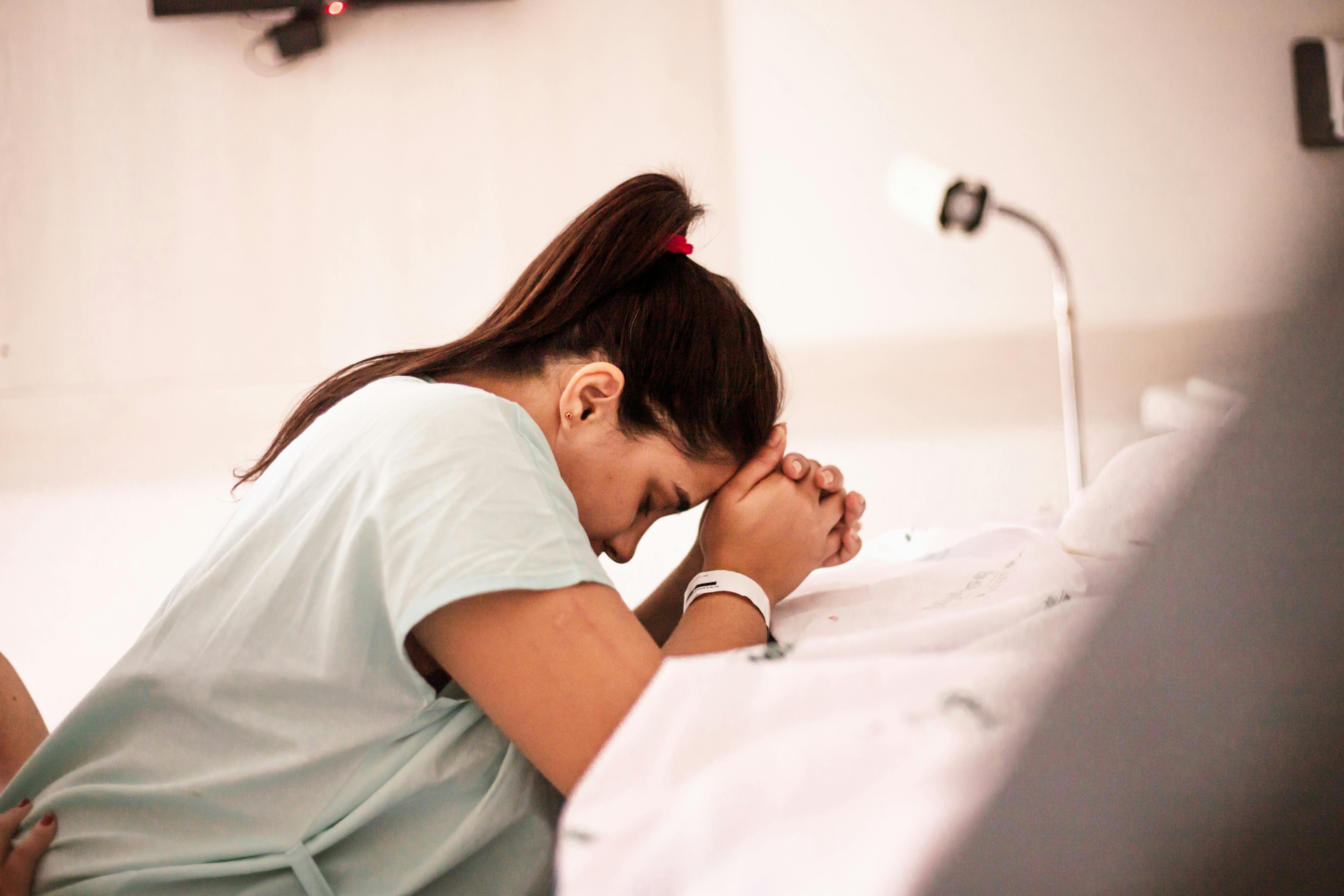 a woman in a hospital bed praying