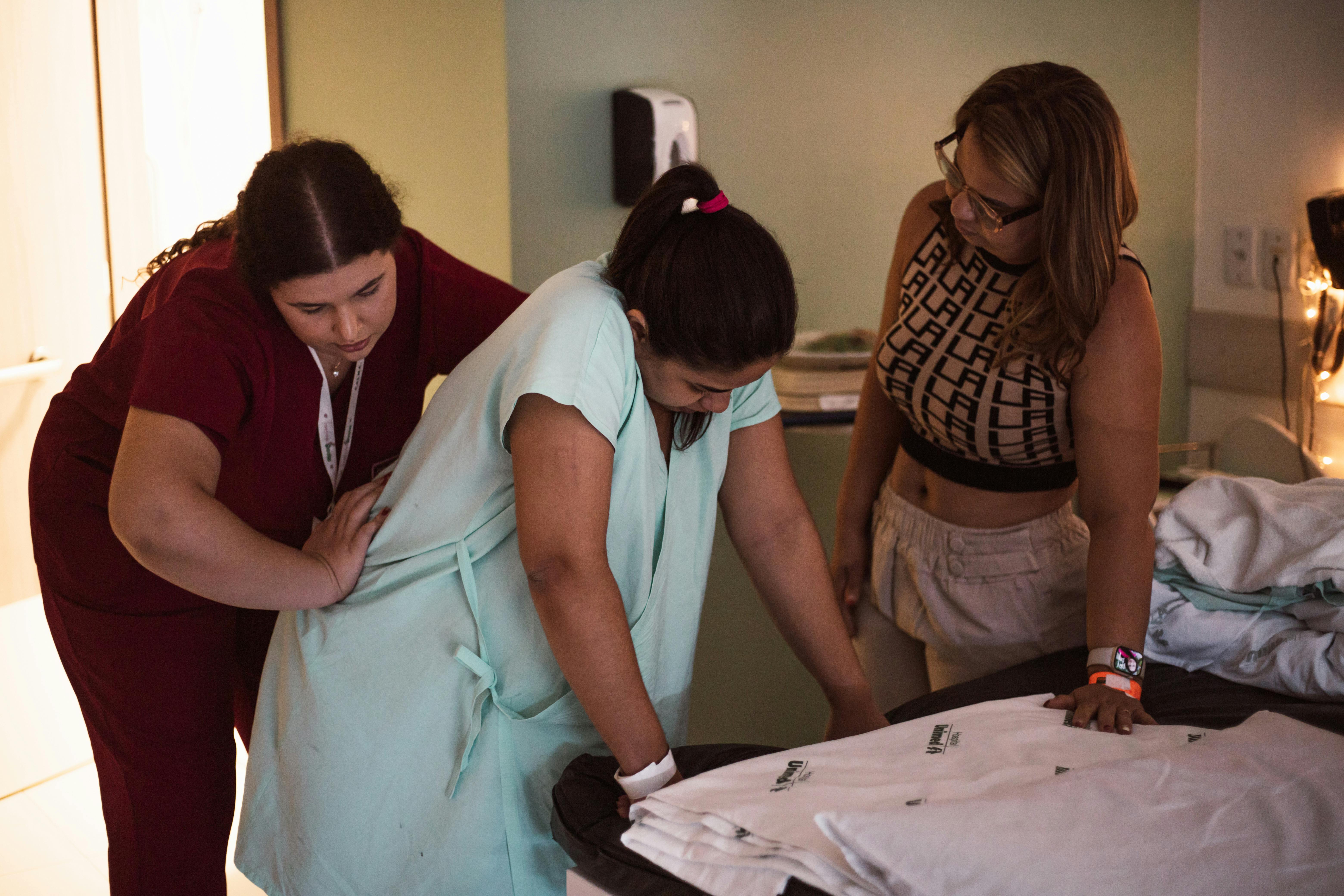 three women are helping a woman with a baby