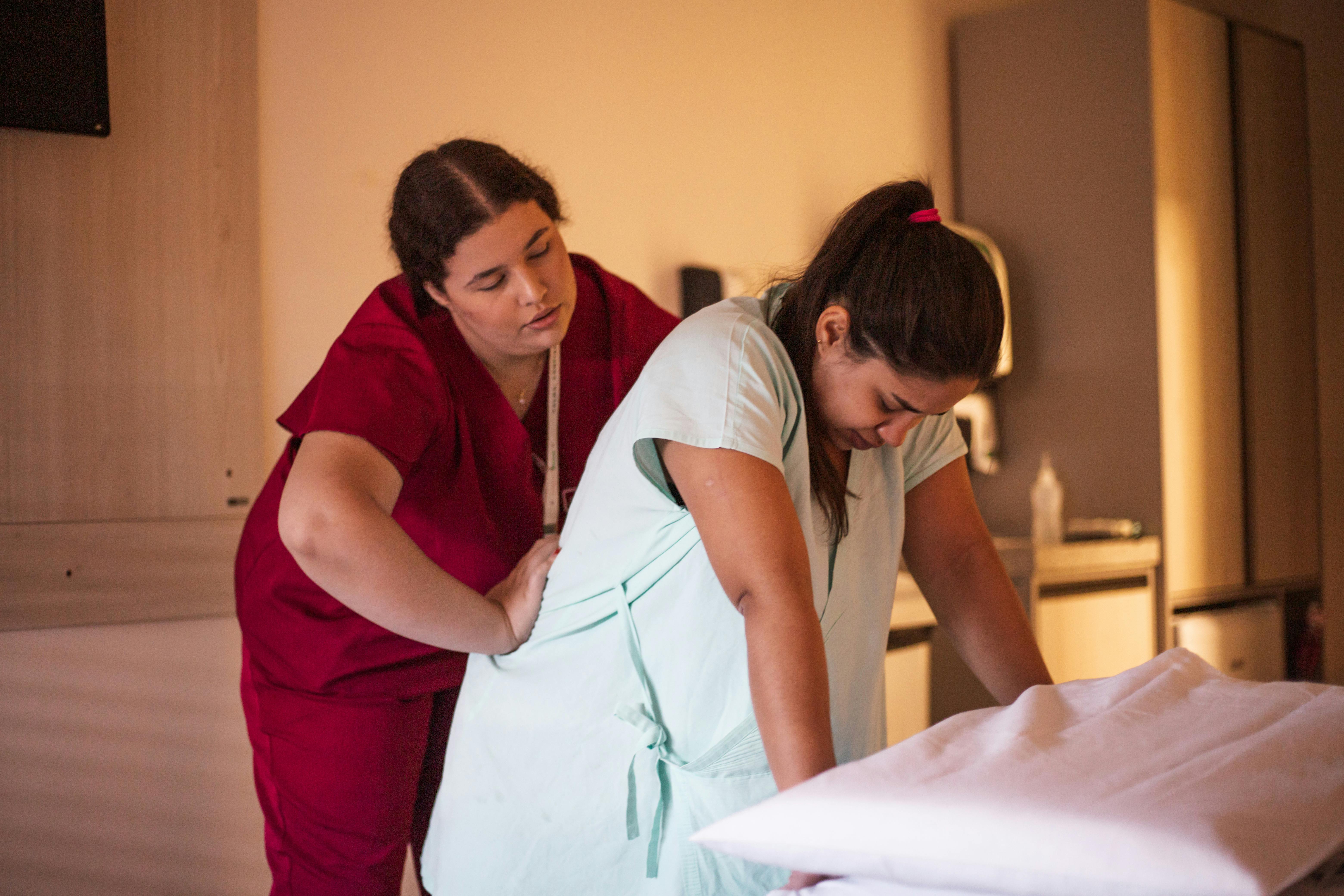 a woman in a red uniform is helping a woman in a bed