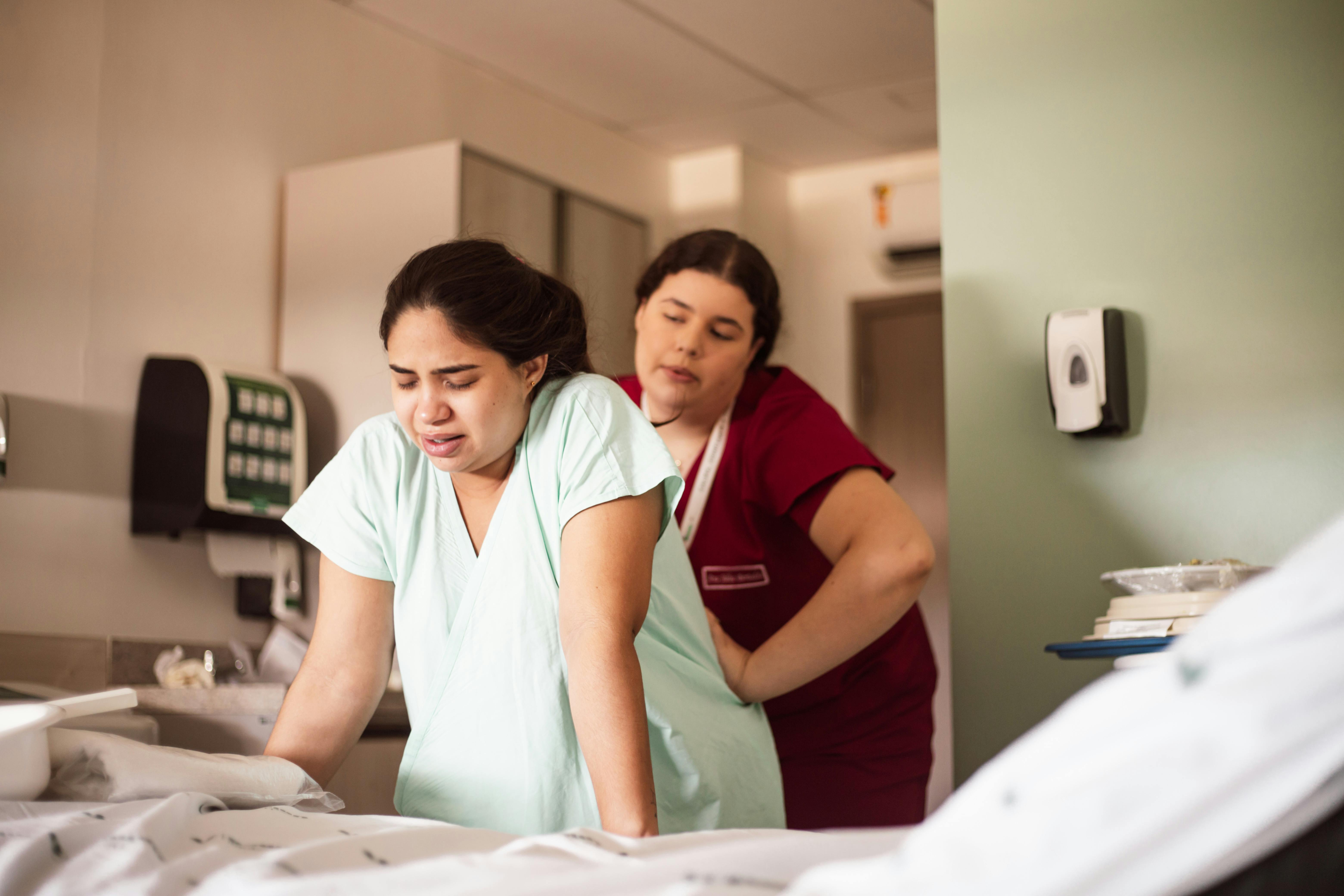 two nurses in a hospital room looking at a patient