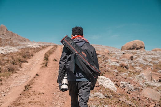 Photographer hiking uphill on a rocky path in Oromia, Ethiopia with camera gear.