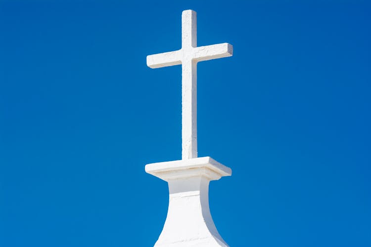 A White Cross On Top Of A Church Steeple