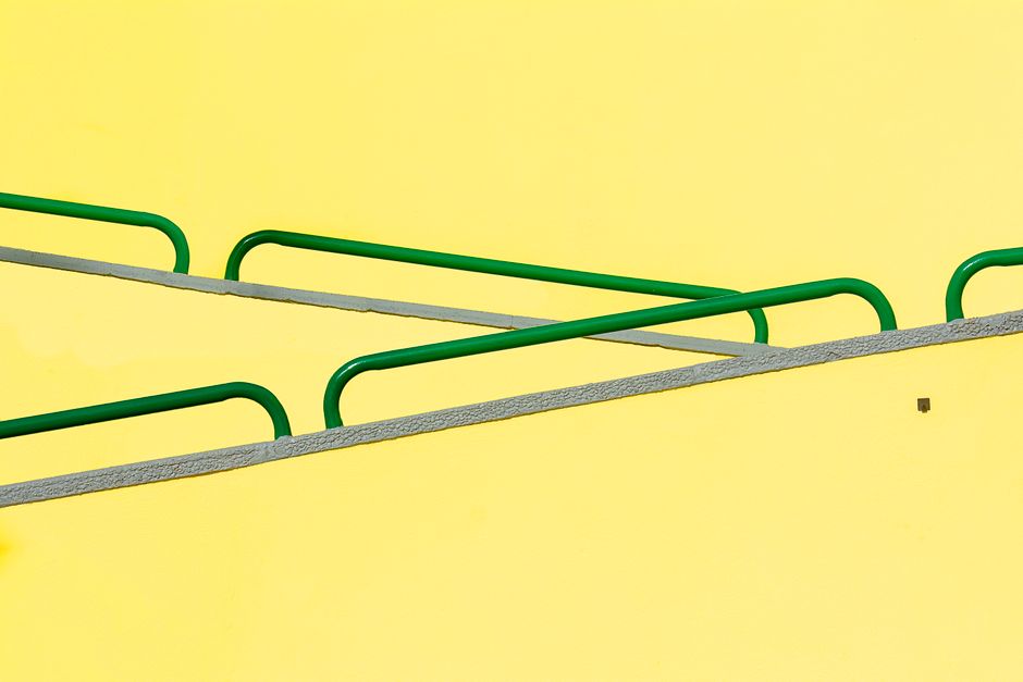 Artistic composition of green rails against a bright yellow background, perfect for modern design concepts.